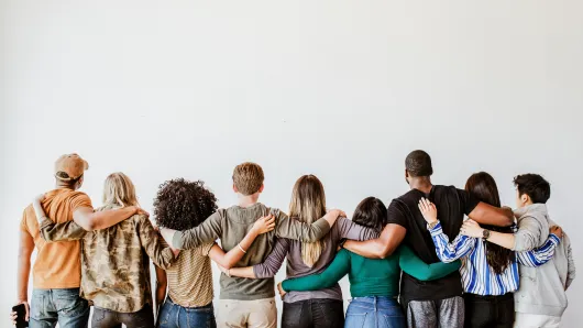 Group of people with their arms around one another. 