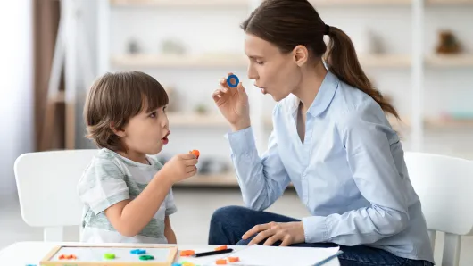 Little boy learning letter O with a teacher.