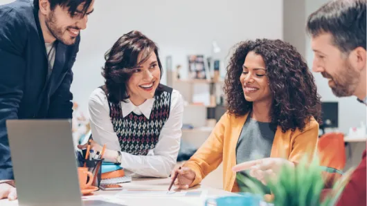 A group of smiling educators collaborate at a table 