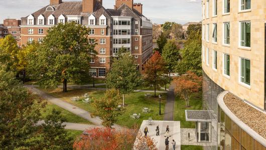 A scenic view of NBS campus with a mix of modern and historic buildings, lush green spaces, and  participants congregate in front of Tata