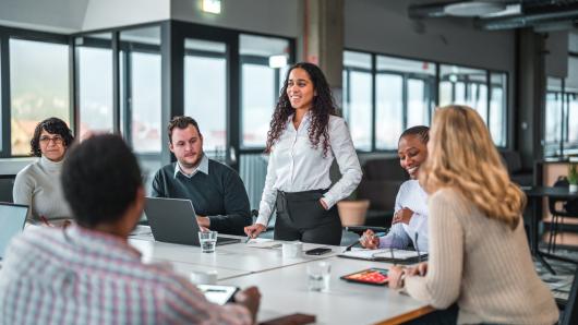 woman speaking to group of people in conference room
