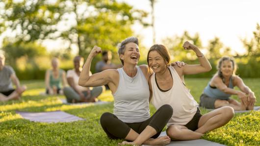 Two women showing their muscles while at a yoga class.