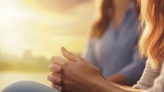 A person clasping their hands together with the sunlight in the upper left corner.