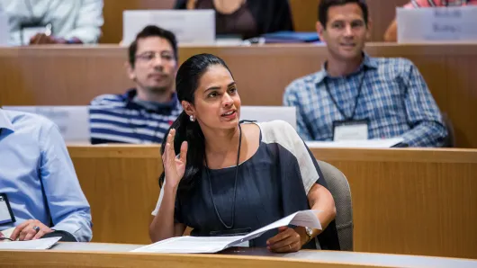 Female executive raises hand to participate in classroom lecture discussion