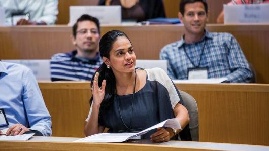 Female executive raises hand to participate in classroom lecture discussion