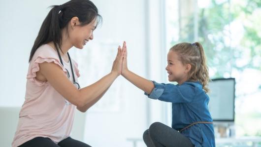A health care provider high-fiving a child.
