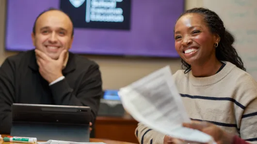 Two professionals reviewing documents during a group discussion