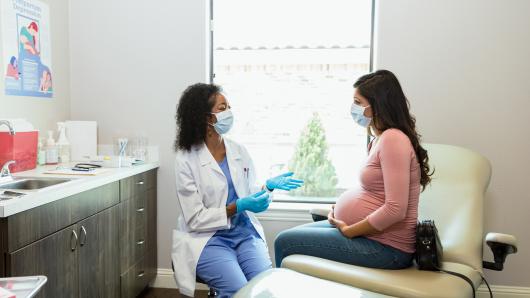Doctor interacting with a pregnant female patient.