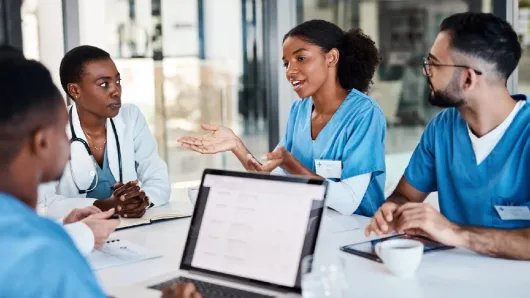 Health care professionals sitting at a table, having a discussion
