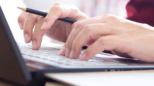 Hands typing at laptop