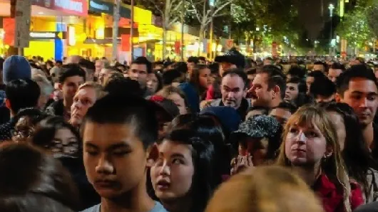A crowd of people in an urban environment at night.