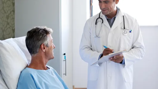 Doctor talking to patient in hospital bed.