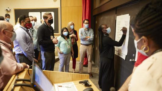 A group of physicians standing in a classroom observing an instructor