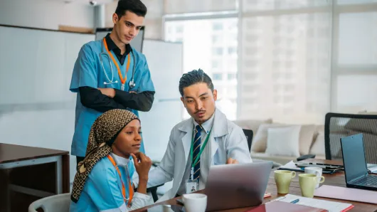 Health care workers gathered around a laptop sharing information
