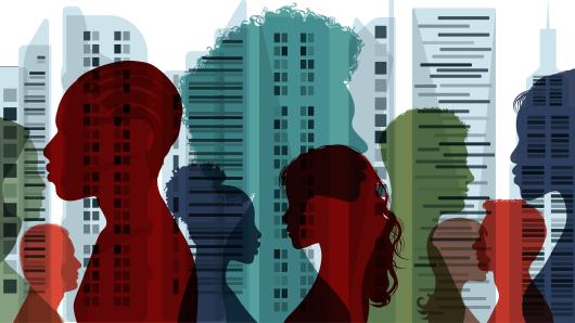 Illustration: a series of multicolored silhouettes of people's profiles superimposed in front of a scene of city skyscrapers