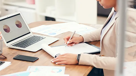 Woman sitting at desk writing on notepad