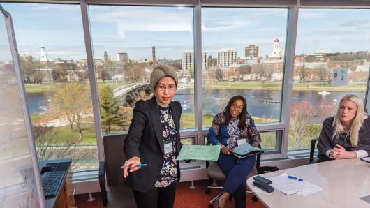 A diverse group of female executives in a conference room overlooking the charles river