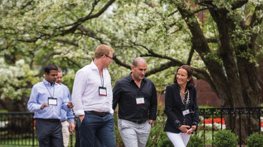 A diverse group of five executives walking on the HBS campus