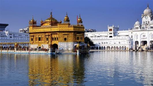 The golden temple, a white and gold building sitting behind water