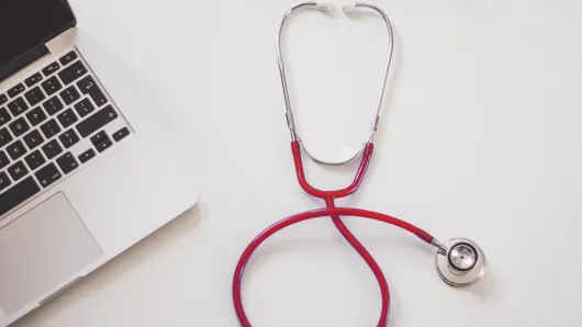 A stethoscope next to a laptop.