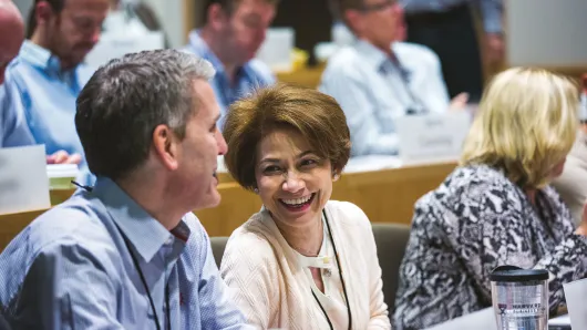 Female executive talking with a male executive in a HBS executive education classroom