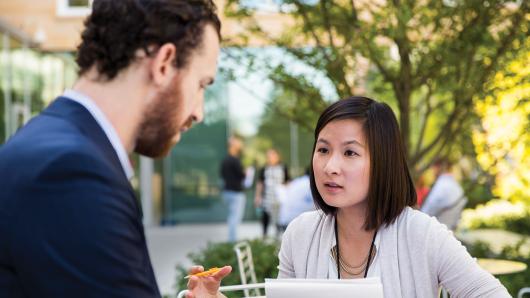 an asian female executive talking with a white male executive