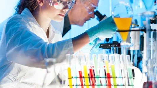 Medical personnel in lab with microscopes.