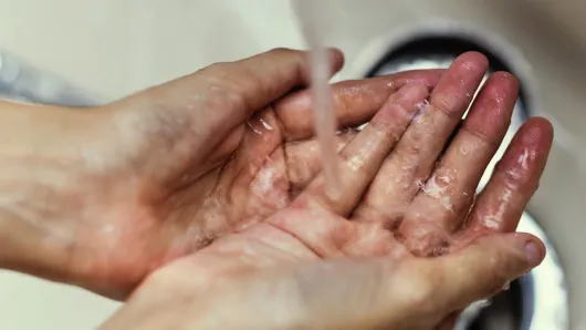 Person washing hands over sink.