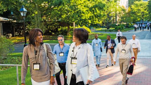 A diverse group of executives walking on the HBS campus