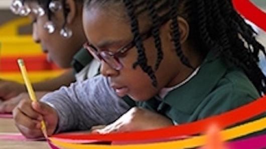 Young student writing at desk with a pencil